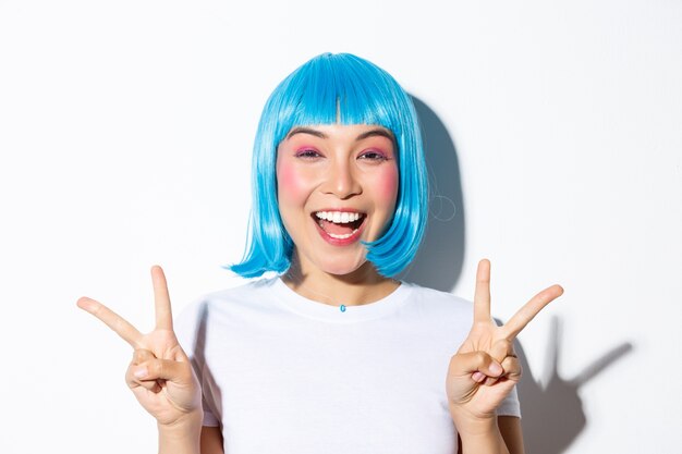 Primer plano de hermosa chica asiática emocionada mostrando gesto de paz y sonriendo