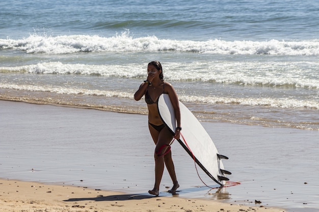Primer plano de una hermosa joven con una tabla de surf en la playa
