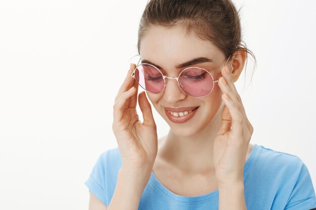 Primer plano de hermosa mujer femenina ponerse gafas de sol y sonriendo sensualmente