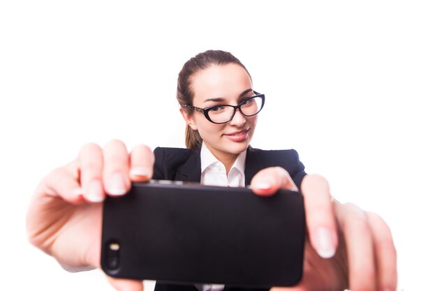 Primer plano de una hermosa mujer de negocios juguetona haciendo foto selfie en pared blanca aislada