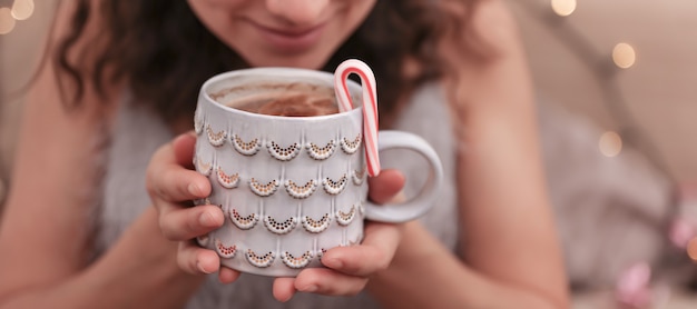 Foto gratuita primer plano de una hermosa taza de navidad en manos femeninas sobre un fondo borroso.