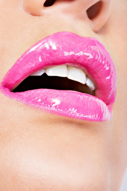 Primer plano Hermosos labios femeninos con lápiz labial rosa. Maquillaje de brillo brillante de moda glamour.