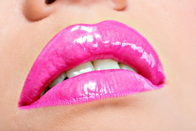 Primer plano Hermosos labios femeninos con lápiz labial rosa. Maquillaje de brillo brillante de moda glamour.