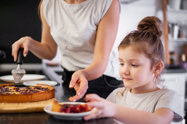 Primer plano hija y madre compartiendo pastel juntos