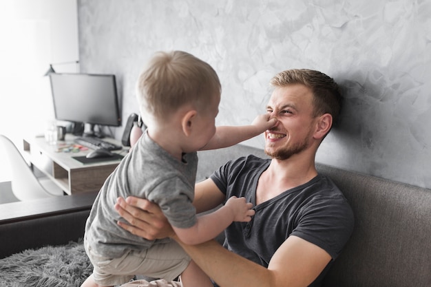 Foto gratuita primer plano del hijo sosteniendo la nariz de su padre mientras juega con él