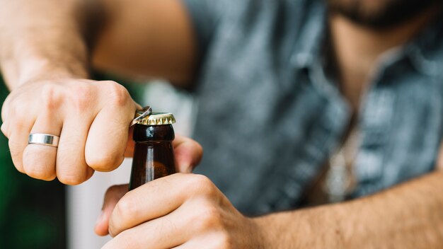 Primer plano de hombre abriendo el tapón de la botella con el abrelatas