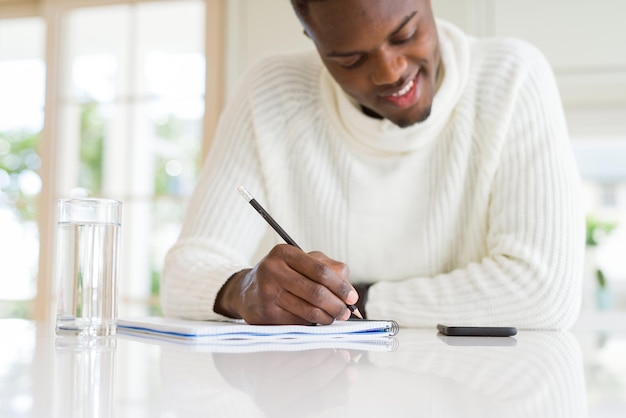 Primer plano de un hombre africano escribiendo una nota en un papel sonriendo confiado