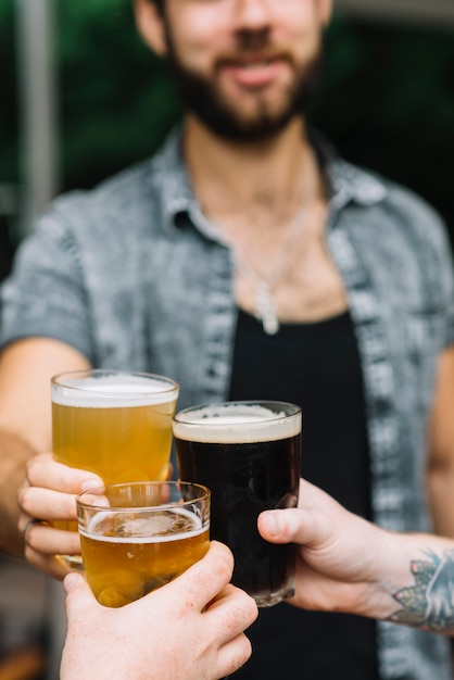 Primer plano de hombre animando los vasos de cerveza con sus amigos