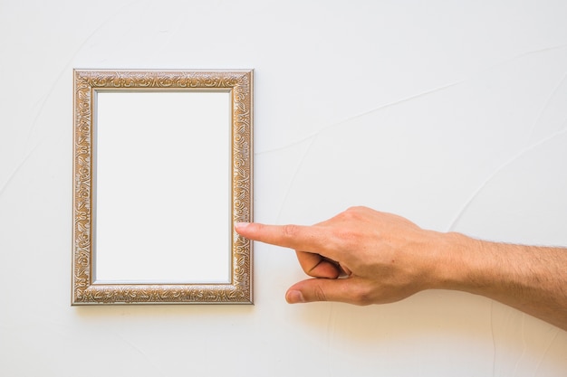 Primer plano de hombre apuntando al marco dorado blanco en pared