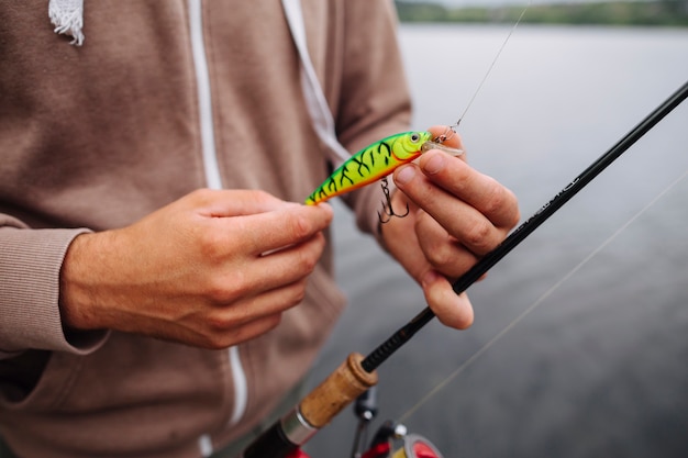 Primer plano del hombre atar señuelo en gancho de pesca