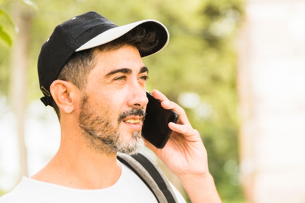 Foto gratuita primer plano de hombre barba llevaba gorra hablando por teléfono móvil