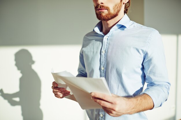 Primer plano de hombre con barba sujetando un documento