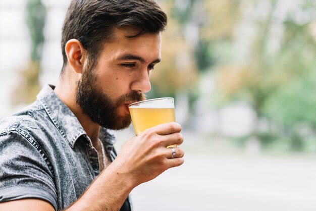 Primer plano, de, hombre, bebida, vaso de cerveza, en, aire libre