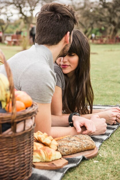 Primer plano de un hombre besando a su novia en la frente en el parque