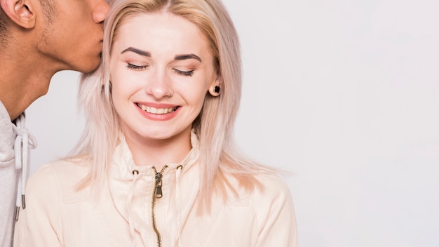 Primer plano de hombre besando a su novia sonriente sobre fondo blanco