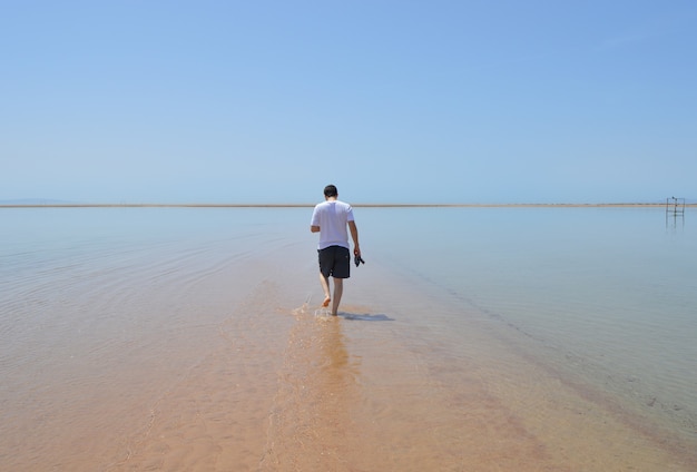 Primer plano de un hombre caminando por la playa en un día soleado