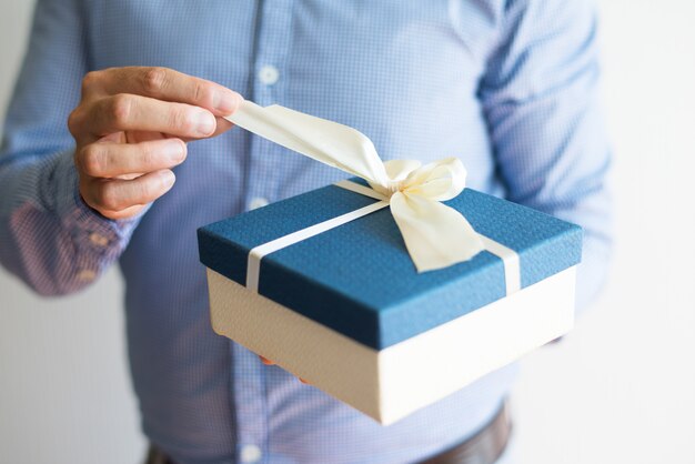 Primer plano de hombre en camisa abriendo regalo de cumpleaños