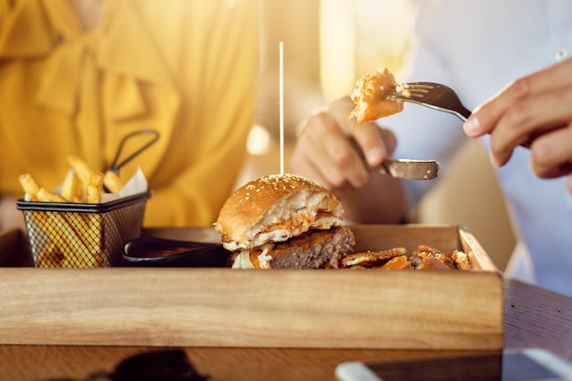 Primer plano de hombre comiendo hamburguesa con queso en un almuerzo con su novia