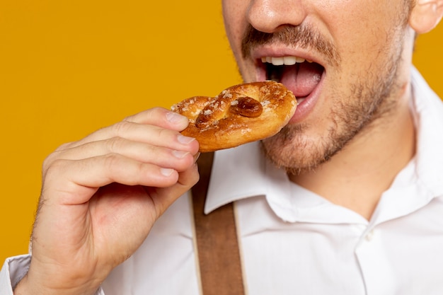 Primer plano del hombre comiendo pretzel alemán