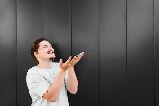 Primer plano de un hombre disfrutando de la música en el teléfono móvil a través de auriculares