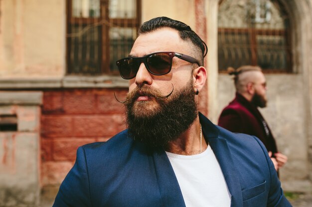 Primer plano de hombre estiloso con barba y gafas de sol