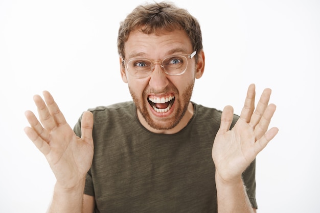 Foto gratuita primer plano de un hombre europeo divertido abrumado emocionado con cerdas en vasos levantando las palmas y gritando de alegría y felicidad siendo sorprendido y alegre con noticias impresionantes posando en camiseta verde oscuro