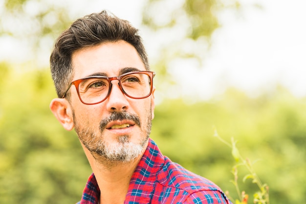 Primer plano de un hombre en gafas rojas mirando a otro lado