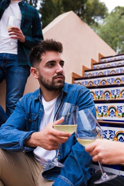 Primer plano de un hombre guapo sentado en la escalera con copa de vino