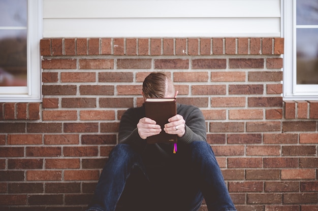 Primer plano de un hombre joven sentado con un libro en las manos