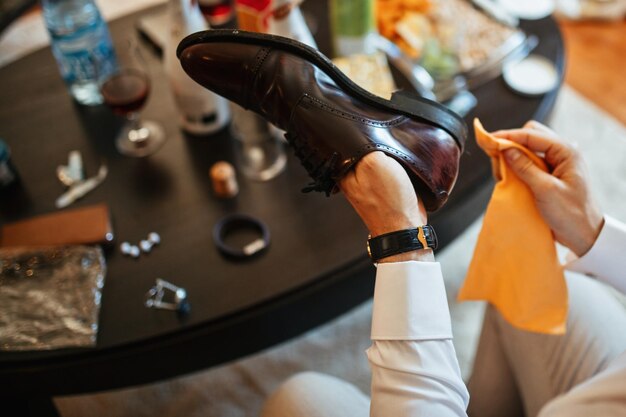 Primer plano del hombre limpiando zapatos mientras se prepara para la ceremonia de boda