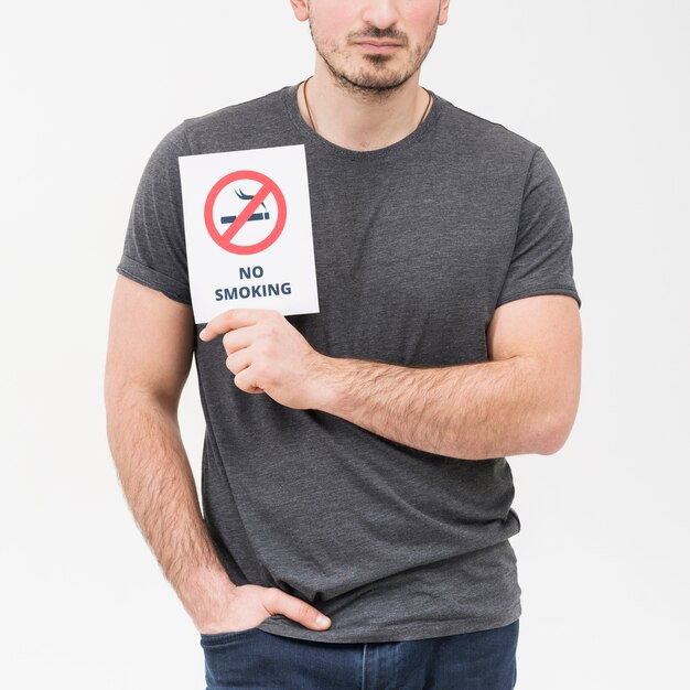 Primer plano de un hombre con las manos en el bolsillo que muestra el cartel de no fumar contra el fondo blanco
