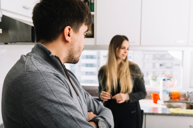 Primer plano de un hombre mirando a la mujer de pie en la cocina