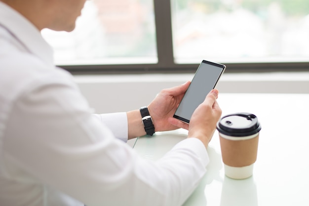 Primer plano de hombre de negocios con dispositivo moderno en el lugar de trabajo