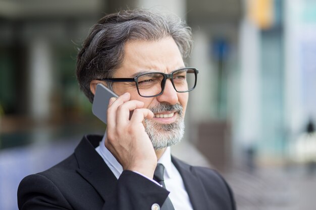 Primer plano de hombre de negocios de mediana edad llamando por teléfono