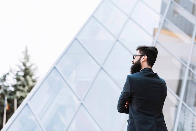 Primer plano de un hombre de negocios de pie delante del edificio corporativo