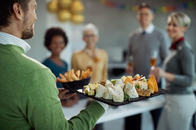 Primer plano de un hombre de negocios que sirve comida durante la fiesta de la oficina