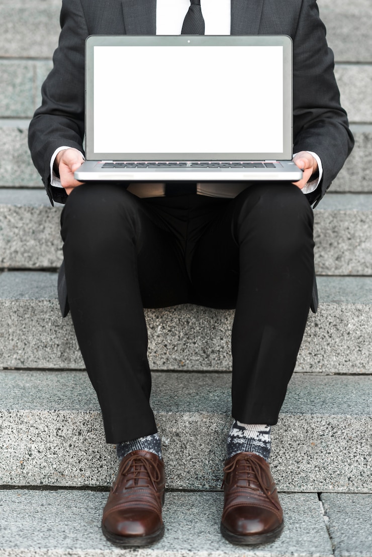 Foto gratuito primer plano de un hombre de negocios sentado en las escaleras con una computadora portátil abierta sobre su regazo