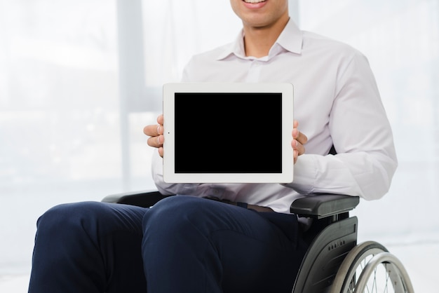 Foto gratuita primer plano de un hombre de negocios sentado en silla de ruedas mostrando tableta digital con pantalla negra