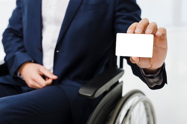 Primer plano de un hombre de negocios sentado en silla de ruedas mostrando tarjeta de visita blanca