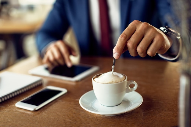 Primer plano de un hombre de negocios tomando una taza de café en una cafetería