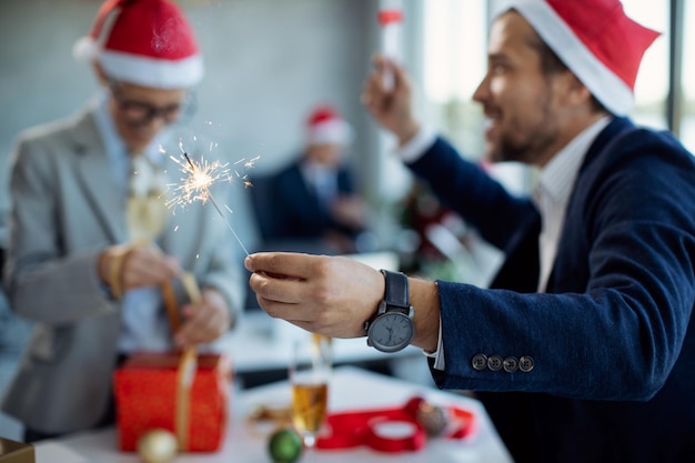 Primer plano de un hombre de negocios usando una bengala en la fiesta de Año Nuevo en la oficina