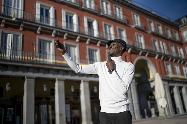 Primer plano de un hombre negro que llevaba un cuello alto y un sombrero tomando un selfie