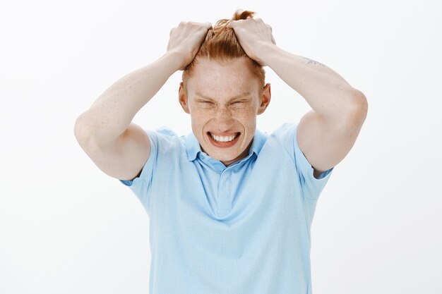 Primer plano de hombre pelirrojo enojado rasga el cabello en la cabeza y parece angustiado, sintiéndose bajo presión