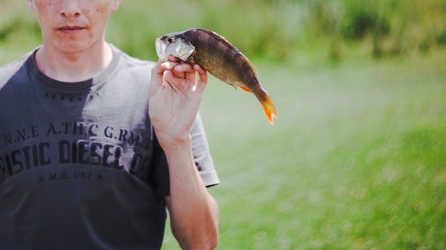 Primer plano de hombre con pescado fresco capturado en la mano