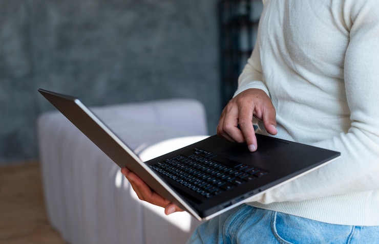 Foto gratuito primer plano de hombre de pie usando laptop