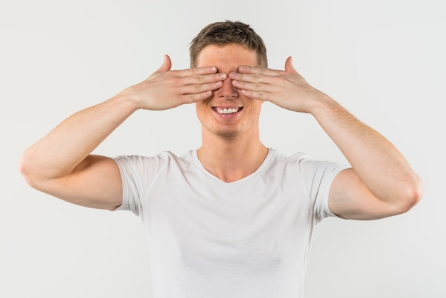 Primer plano de un hombre que cubre sus ojos con dos manos aisladas sobre fondo blanco