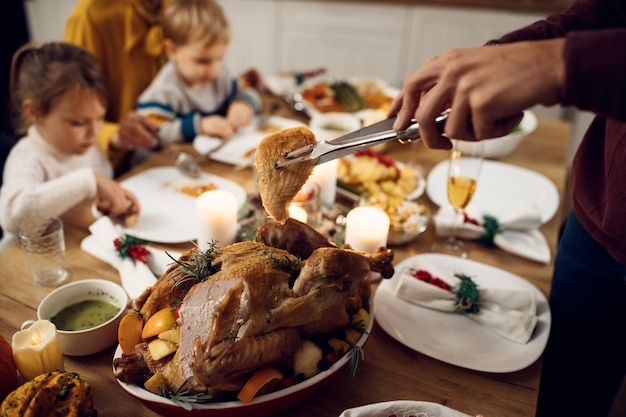 Primer plano de un hombre que sirve carne de pavo durante una comida familiar en Acción de Gracias