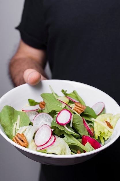 Foto gratuita primer plano del hombre que sostiene un tazón de ensalada