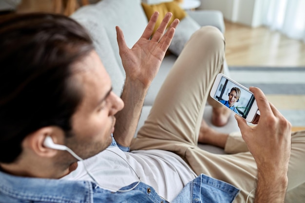 Primer plano de un hombre que tiene una videollamada con un médico por teléfono móvil mientras está sentado en casa