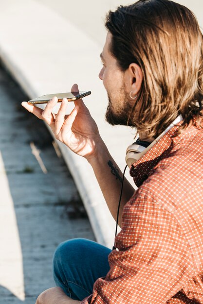 Primer plano de un hombre que usa el reconocimiento de voz de un teléfono inteligente en línea